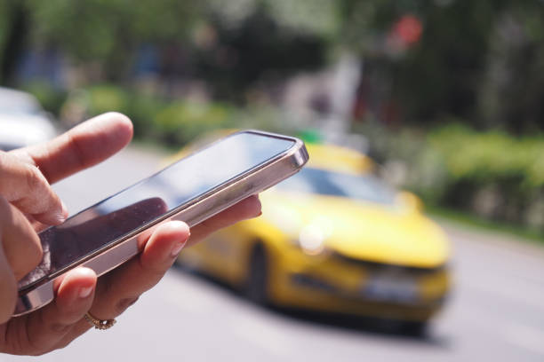 An individual is utilizing a smartphone to conveniently call for a taxi on a bustling city street