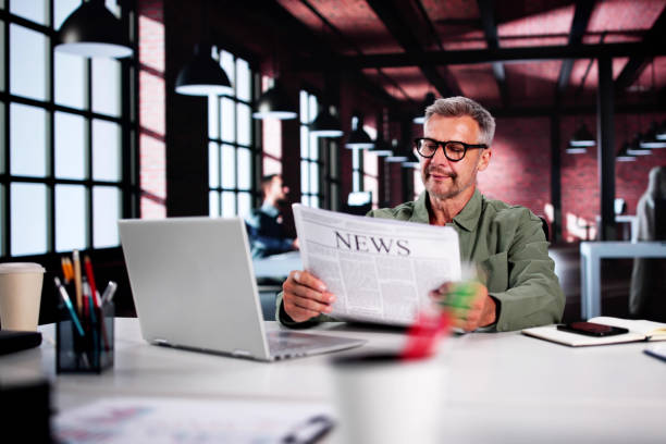 istock Businessman Reading Newspaper At Office Desk 2165903934