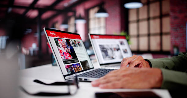 istock Watching Online News Article On Mobile Phone And Laptop 2165903969