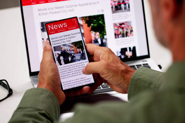 istock Watching Online News Article On Mobile Phone And Laptop 2165903998