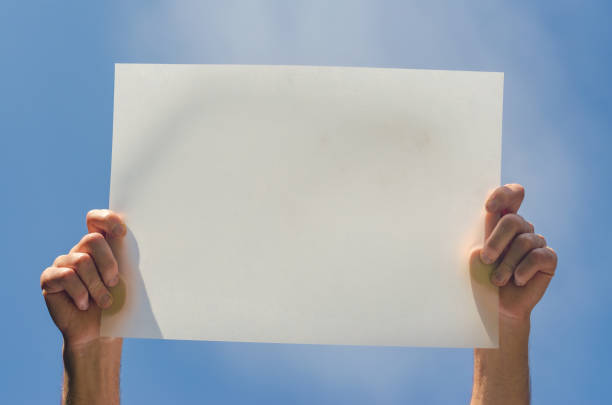 istock male hands hold white empty poster on blue sky background 2165905572