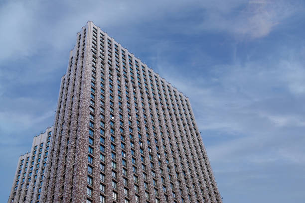A tall building against a background of blue, cloudy sky. The building is very tall and has many windows.