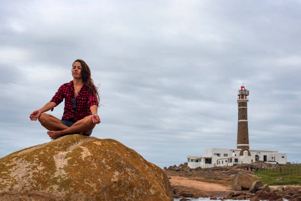 Woman meditating on a rock on Cabo Polonio beach in Uruguay