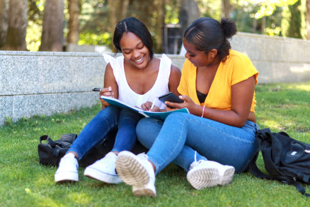istock Two Hispanic women students sitting together on the grass, collaborating on a study project 2165923284