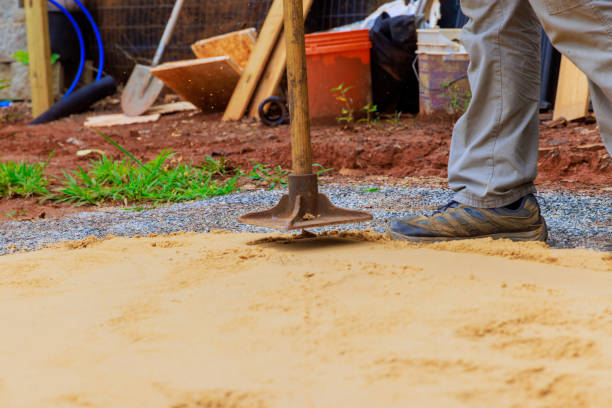 istock Using a manual rammer, worker tamps sand prior to constructing swimming pool 2165926174
