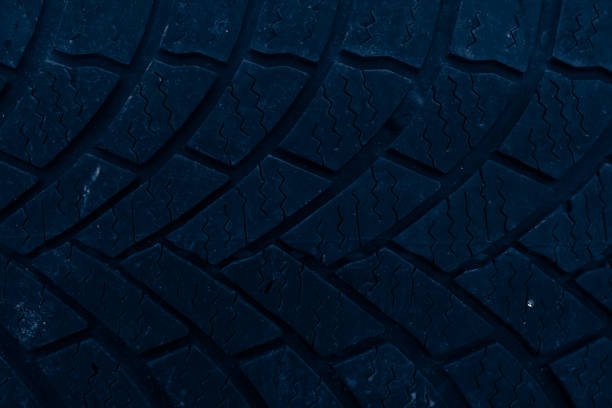 small rocks stuck in car tire tread, closeup.