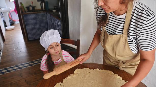 Mother and daughter baking together in kitchen making dough