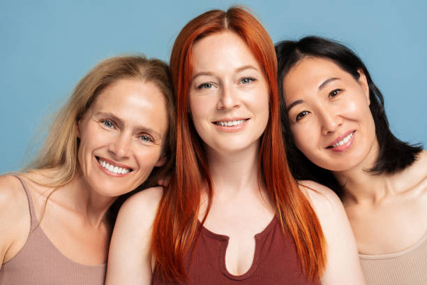 istock Three confident women smiling and embracing looking at camera, posing isolated on blue background 2165935527