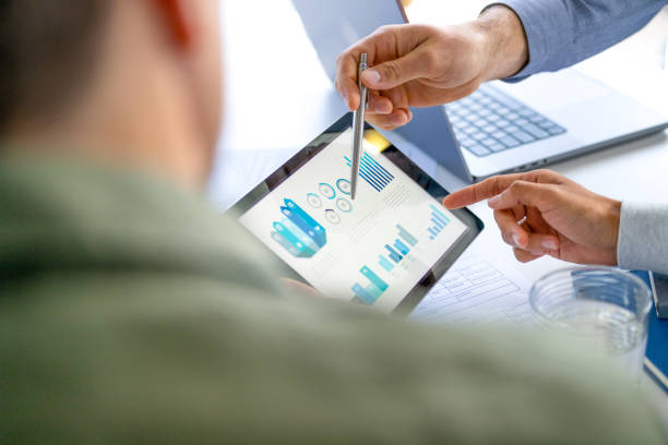 istock Three  business men meeting and looking at financial data, charts and graphs on a digital tablet and a laptop computer. 2165937963