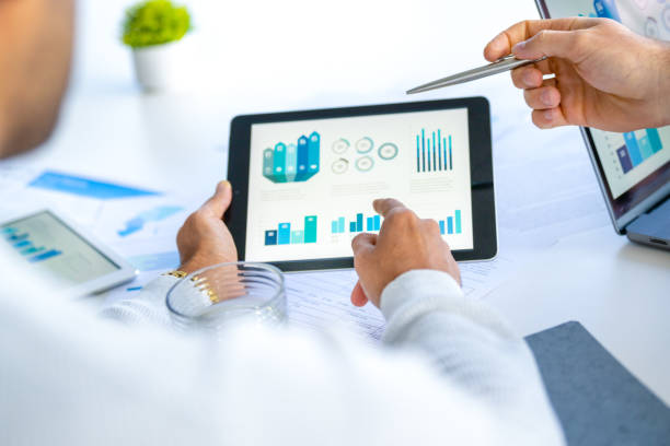 istock Two  business men meeting and looking at financial data, charts and graphs on a digital tablet and a laptop computer 2165937982