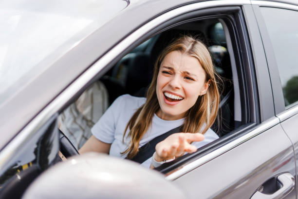 istock Angry young woman driver shouting at another driver while driving a car 2165941197