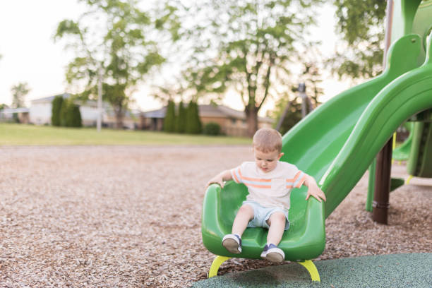 A boy rides down a slide in a children's playground