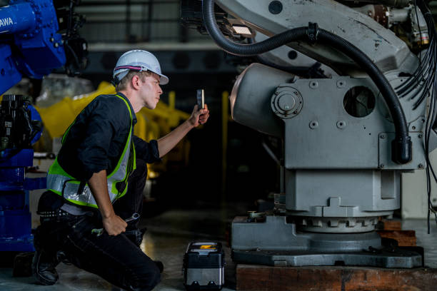 istock male engineer workers maintenance automatic robotic arm machine in a factory. worker checking and repairing automatic robot hand machine. technician worker check for repair factory machine. 2165948060