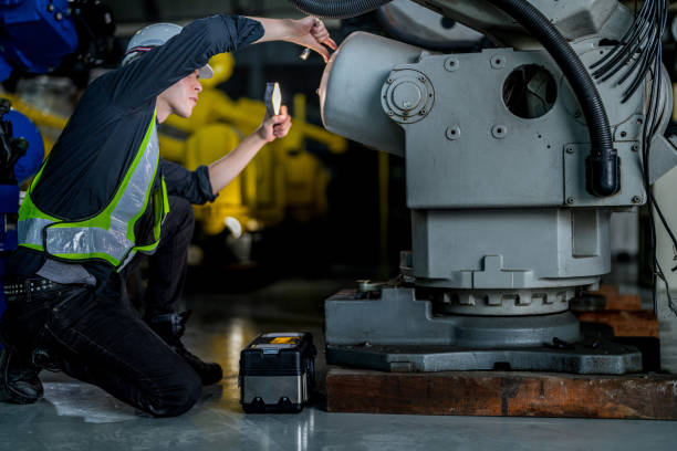 istock male engineer workers maintenance automatic robotic arm machine in a factory. worker checking and repairing automatic robot hand machine. technician worker check for repair factory machine. 2165948207