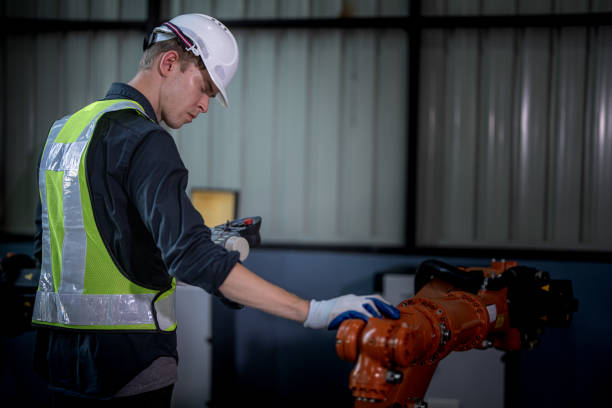 team engineers inspecting on machine with smart tablet. Worker works at heavy machine robot arm. The welding machine with a remote system in an industrial factory. Artificial intelligence concept.