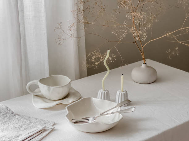 istock Breakfast table - ceramic dishes cup, bowl, plate, thin candles in candlesticks, dried flowers on the table 2165950303