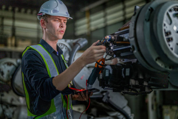 istock male engineer workers maintenance automatic robotic arm machine in a factory. worker checking and repairing automatic robot hand machine. technician worker check for repair factory machine. 2165950709