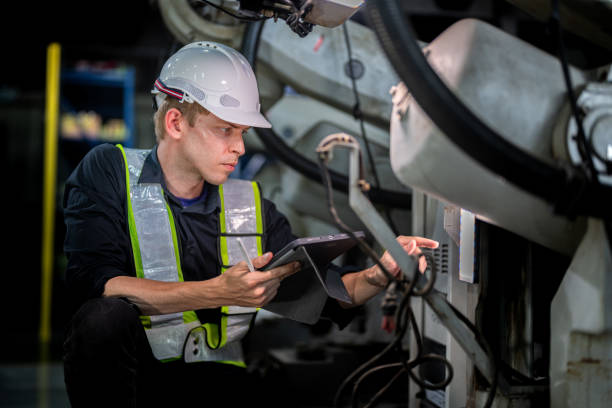 istock male engineer workers maintenance automatic robotic arm machine in a factory. worker checking and repairing automatic robot hand machine. technician worker check for repair factory machine. 2165950818