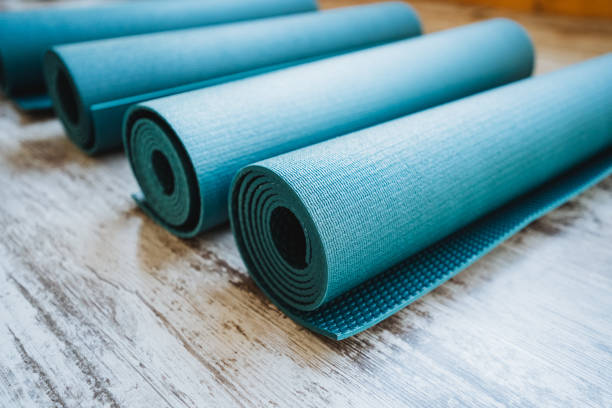 istock Three azure yoga mats rest on wood floor, rolled up 2165951407