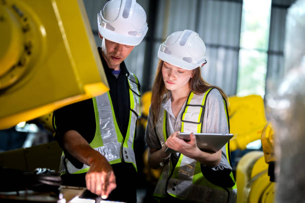 istock team engineers inspecting on machine with smart tablet. Worker works at heavy machine robot arm. The welding machine with a remote system in an industrial factory. Artificial intelligence concept. 2165951575