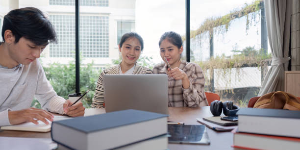 Group of Student Study Together in a Modern Library with Laptops and Books