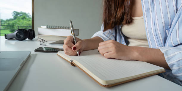 istock Young Student Studying Online at Home with Notebook and Laptop, Focused on Learning and Taking Notes 2165956345