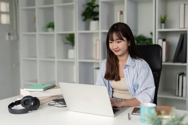 istock Young Student Studying Online at Home with Laptop and Books in a Modern Home Office Setting 2165956381