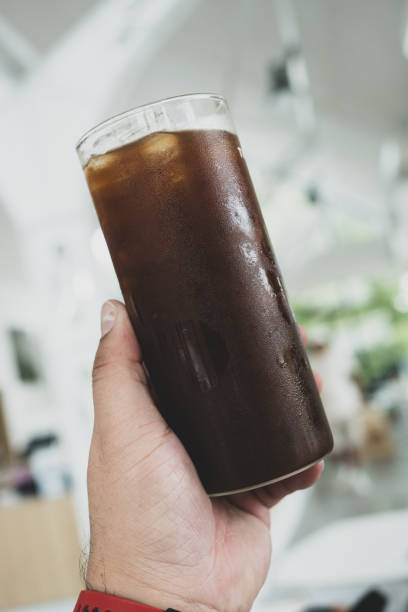 istock Ice cold delicious black coffee in tall glass on man hand 2165957241