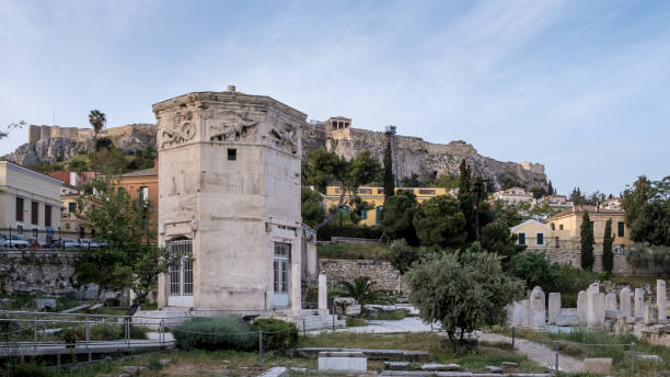 View of the Tower of the Winds, an octagonal clock tower in the Roman Agora of Athens, Greece View of the Tower of the Winds, an octagonal clock tower in the Roman Agora of Athens, made of Pentelic marble. Named for the eight large reliefs of wind gods on its top, it was originally topped by a wind vane and is the only surviving horologium from classical antiquity. Captured at sunrise in Athens' Old Town, the Roman Agora, with the Acropolis in the background, highlights this historic site located north of the Acropolis and east of the Ancient Agora. nike air photos stock pictures, royalty-free photos & images