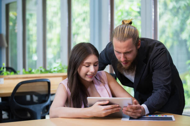 istock Male manager using tablet to give work instructions to female secretary at office. Discussions, brainstorming meetings, work presentations, consulting on business approaches. 2165959844