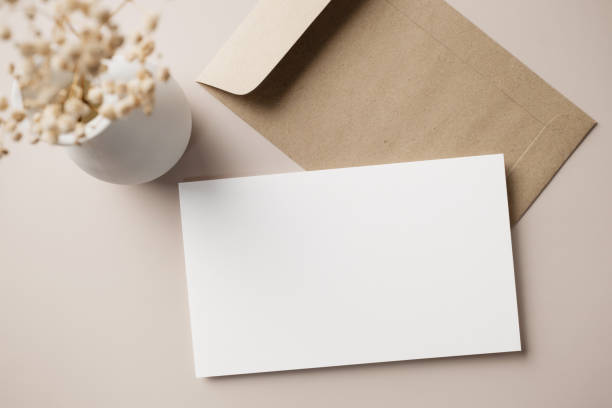 istock White blank greeting or invitation card with ceramic jar decoration and envelope on beige background. Mock up presentation. Flat lay. 2165962283