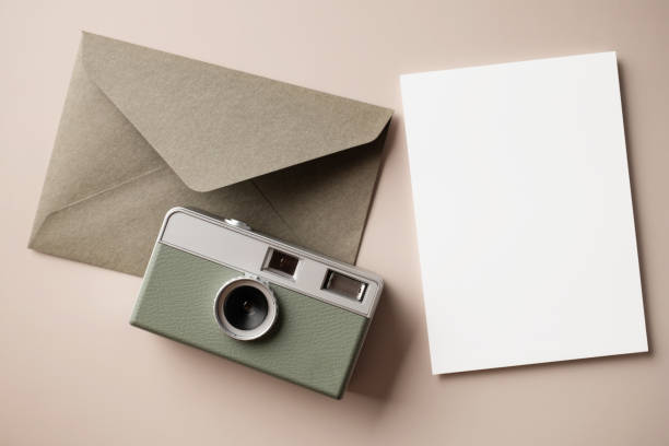 istock White blank greeting or invitation card and envelope with coffee cup, notebook and pencil on beige background. Mockup presentation. Flat lay. 2165962285
