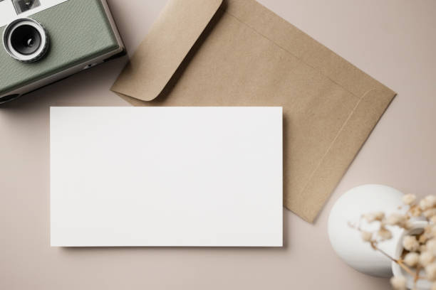 istock White blank greeting or invitation card with ceramic jar decoration and envelope on beige background. Mock up presentation. Flat lay. 2165962293