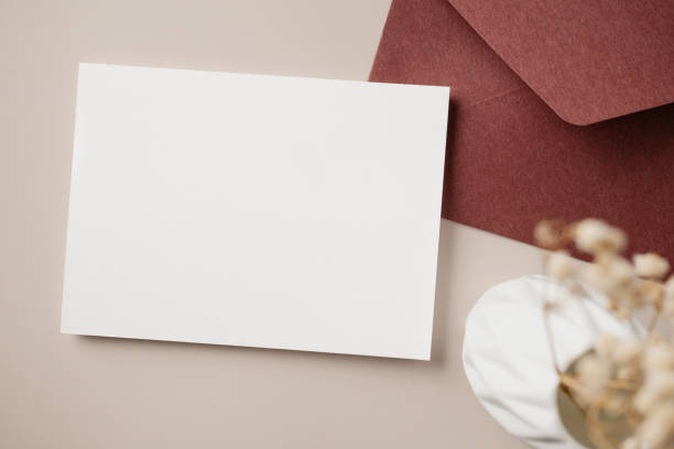 istock White blank greeting or invitation card with ceramic jar decoration and envelope on beige background. Mock up presentation. Flat lay. 2165962297