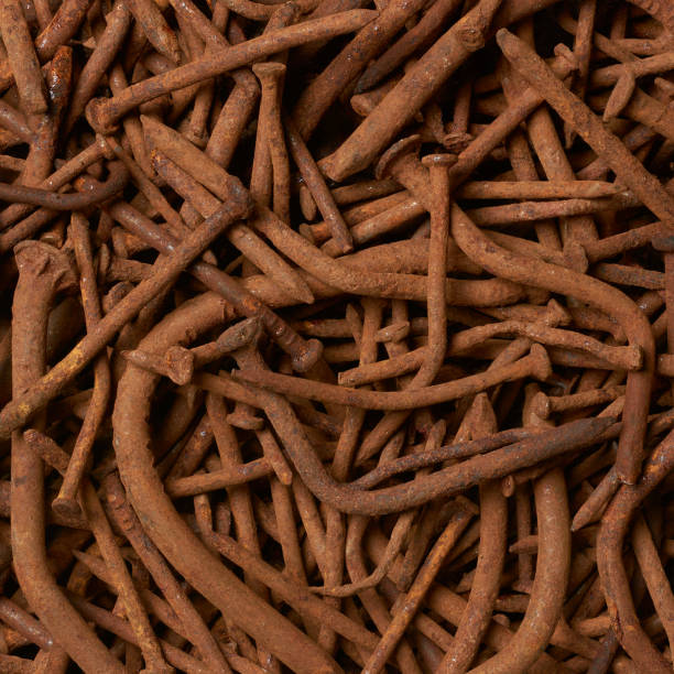 close-up of rusty old warped nails in full frame background, corroded and unusable brownish steel construction fastening material result of rust, bent and broken, failure concept