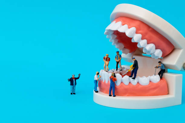 Miniature people cleaning teeth model on blue background