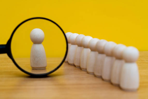 istock Magnifying glass looking at wooden figurine 2165969326