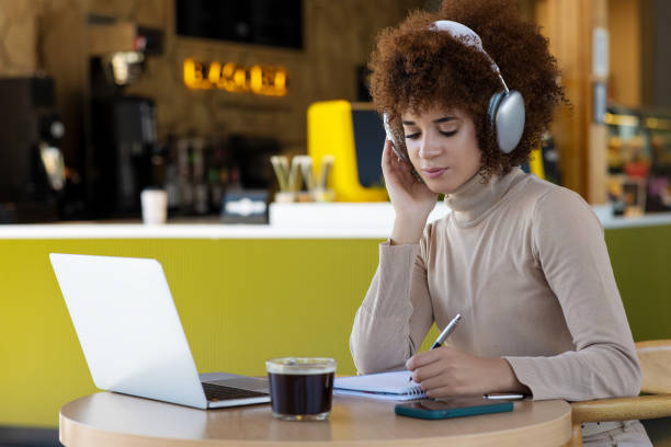 istock Woman using laptop and making notes, sitting at desk at cafe 2165974000
