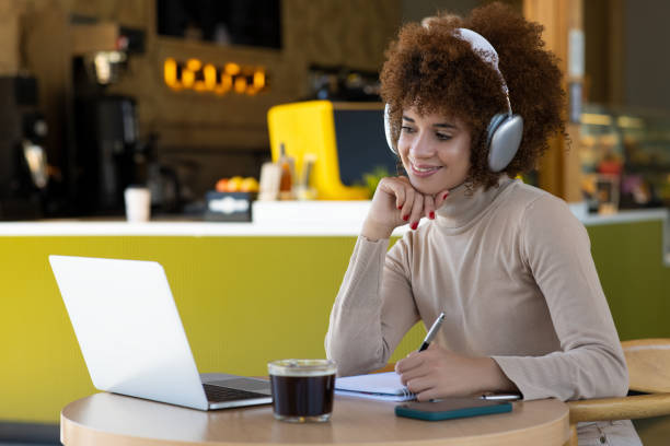 istock Woman using laptop and making notes, sitting at desk at cafe 2165974369
