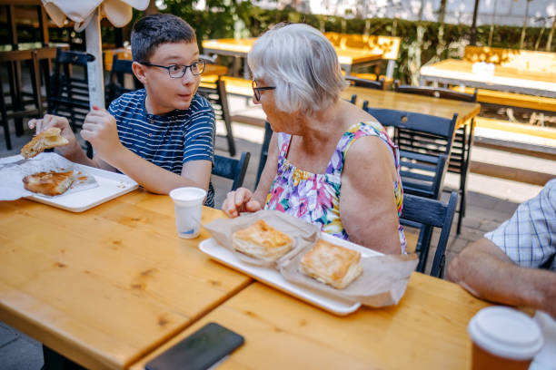 Teenager having breakfast together with grandparents sitting in front of bakery