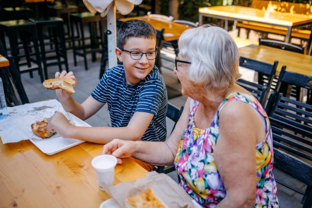 Teenager having breakfast together with grandparents sitting in front of bakery