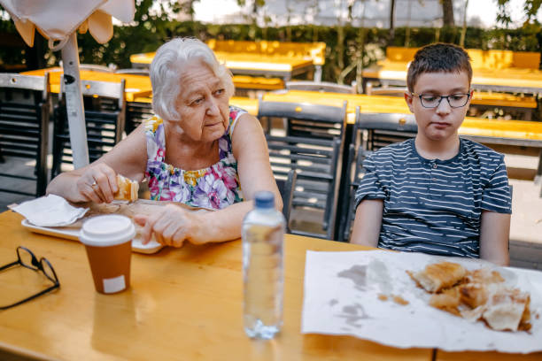 Teenager having breakfast together with grandparents sitting in front of bakery