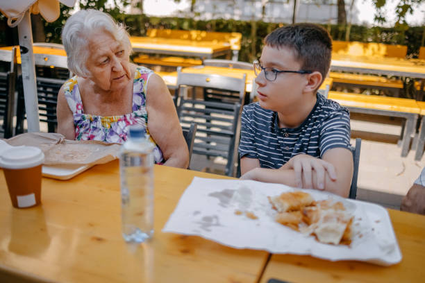 Teenager having breakfast together with grandparents sitting in front of bakery