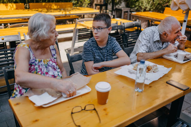 Teenager having breakfast together with grandparents sitting in front of bakery