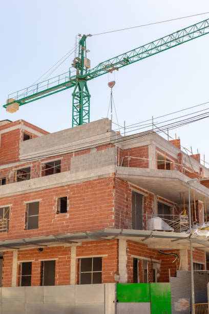 istock Vivid capture of construction site showcasing building in progress with brickwork and crane lifting materials. Ideal for real estate, development projects, and construction industry themes. 2165979676