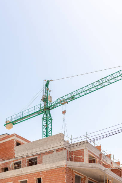 istock Construction site, featuring a towering green crane and partially completed brick building. Perfect for showcasing industrial growth, engineering, and urban development themes. Copy space for text. 2165979681