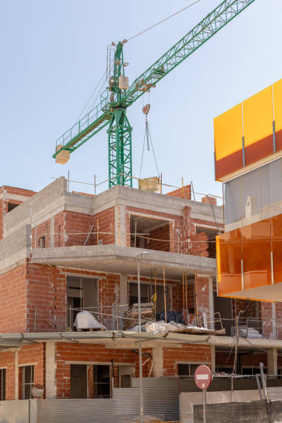 istock Vivid capture of construction site showcasing building in progress with brickwork and crane lifting materials. Ideal for real estate, development projects, and construction industry themes. 2165979707