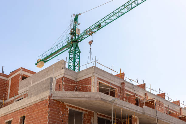 istock Vivid capture of construction site showcasing building in progress with brickwork and crane lifting materials. Ideal for real estate, development projects, and construction industry themes. 2165979711