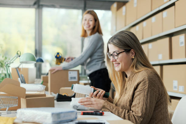 istock Shipping clerk wrapping products with plastic wrap 2165982447
