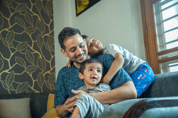 istock Cheerful father playing with sons on sofa at home 2165983147